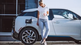 Woman standing in front of her electric vehicle.