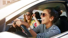 two friends smiling in car driving