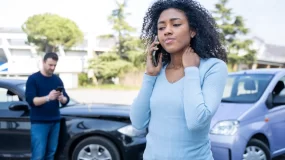 African American woman rubs her neck after a car accident.