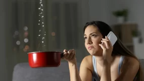 Woman holding a pot to contain a water leak.