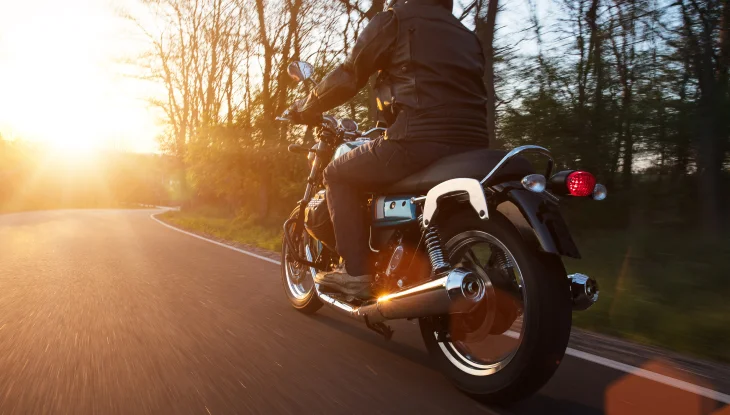 A biker rides down the road during sunset.