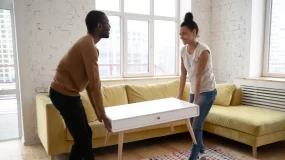Young couple moving furniture into apartment.