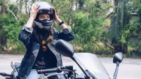 A female biker adjusts her helmet.