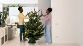 Couple putting up christmas tree in apartment.
