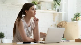 Woman wondering about renters insurance in front of a laptiop.