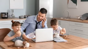 Father at home working with children around.