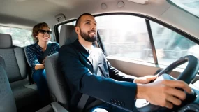 Rideshare driver behind the wheel talking to customer in back seat.