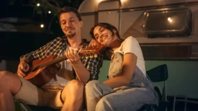 Happy young couple relaxes outside their RV.