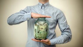 Man's middle body shown with hands holding a jar full of money - car insurance in Georgia