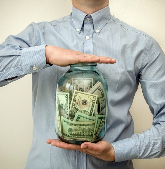 Man's middle body shown with hands holding a jar full of money - car insurance in Georgia